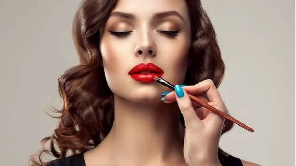a woman applying lipstick on her lips