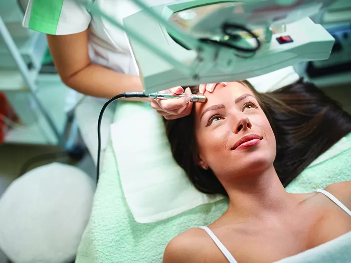 a woman lying on a bed with a machine on her forehead