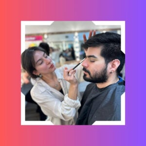 A young woman is completing her makeup certification by working on her male peer at new age spa institute